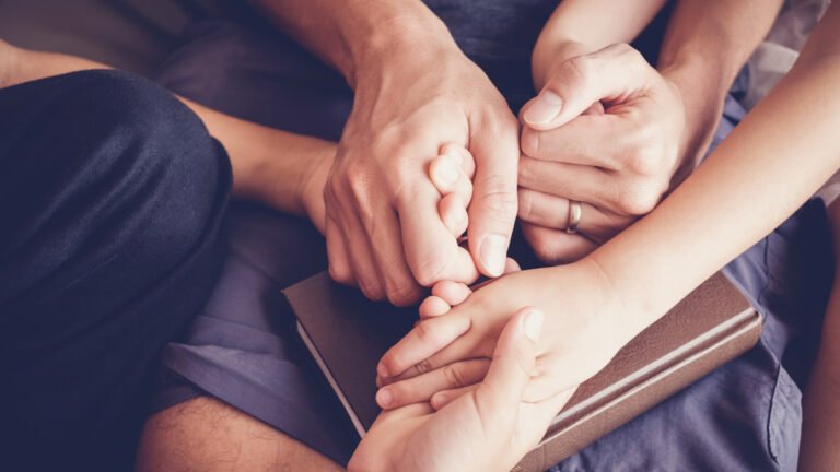Parent and child holding hands praying
